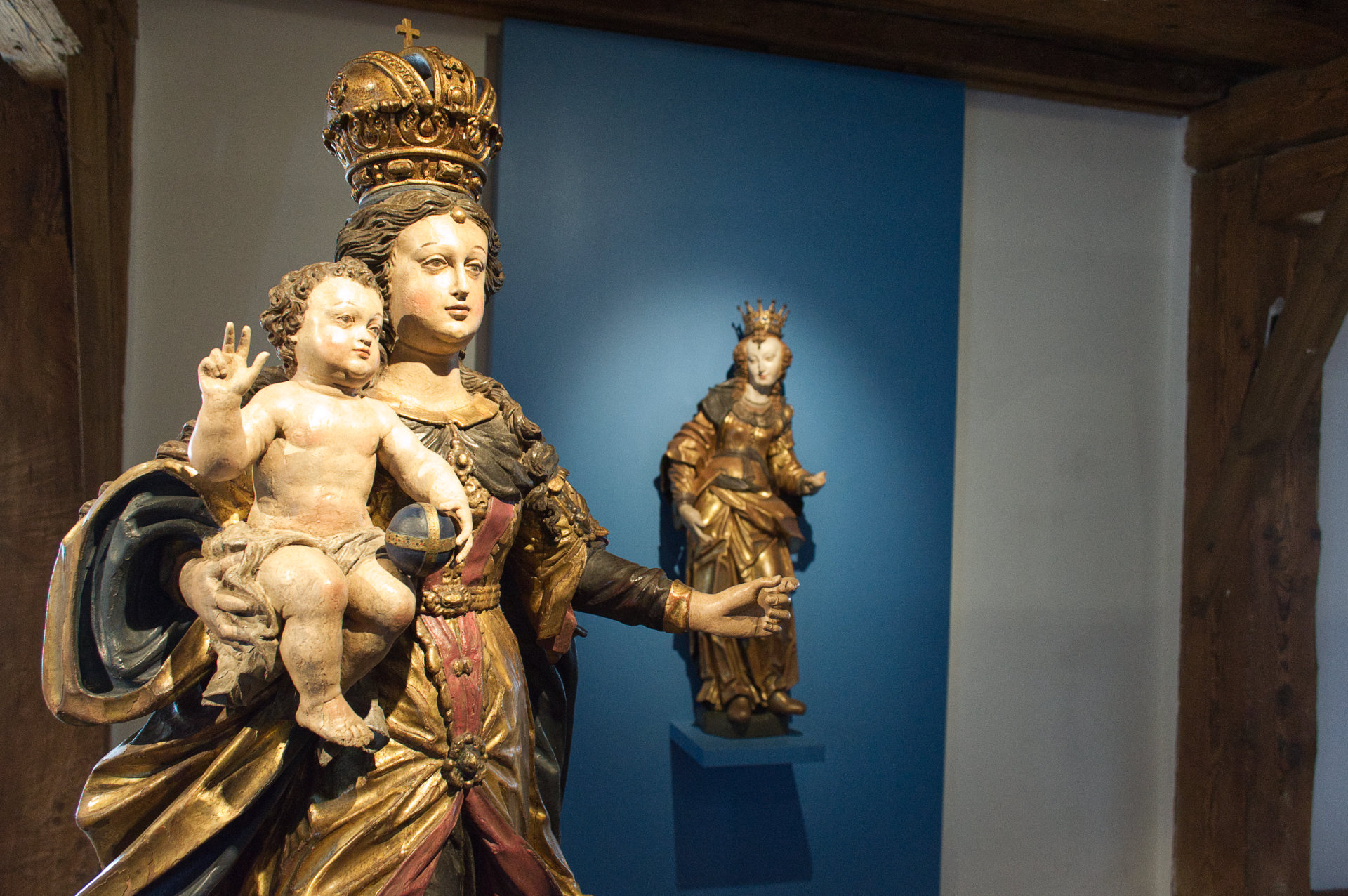 Holzstatuen der Muttergottes mit Kind und Heilige Ursula im Hintergrund